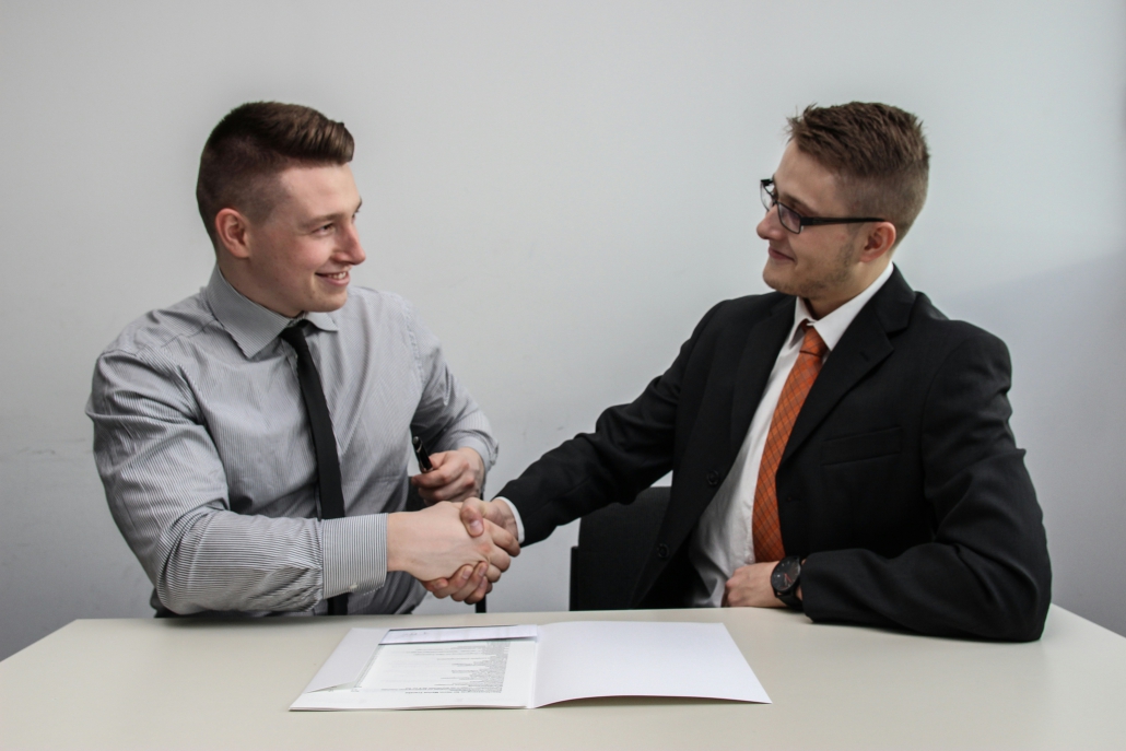 Two men facing each other while shake hands  