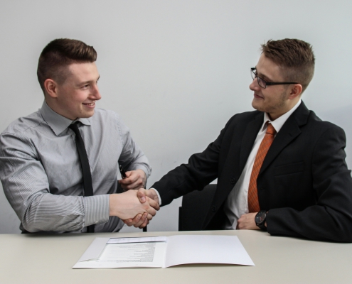 Two men facing each other while shake hands